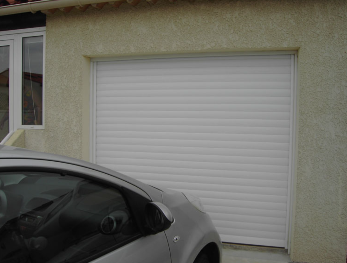 Porte de garage enroulable blanche sur un pavillon, voiture garée devant
