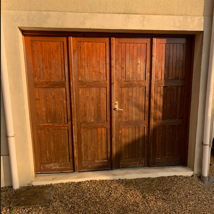 Ancienne porte de garage en bois à quatre vantaux, usée par le temps