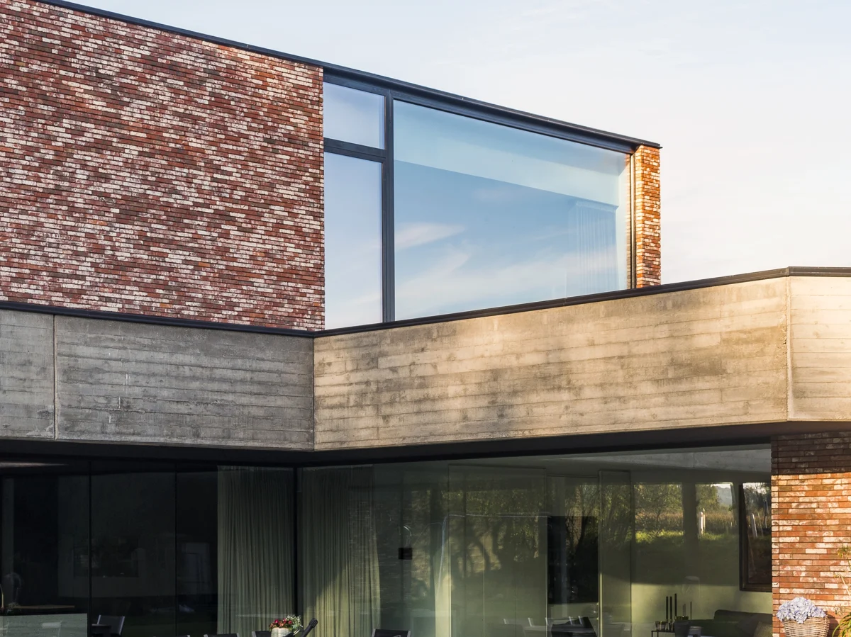 Maison contemporaine en brique avec grandes fenêtres aluminium sombres