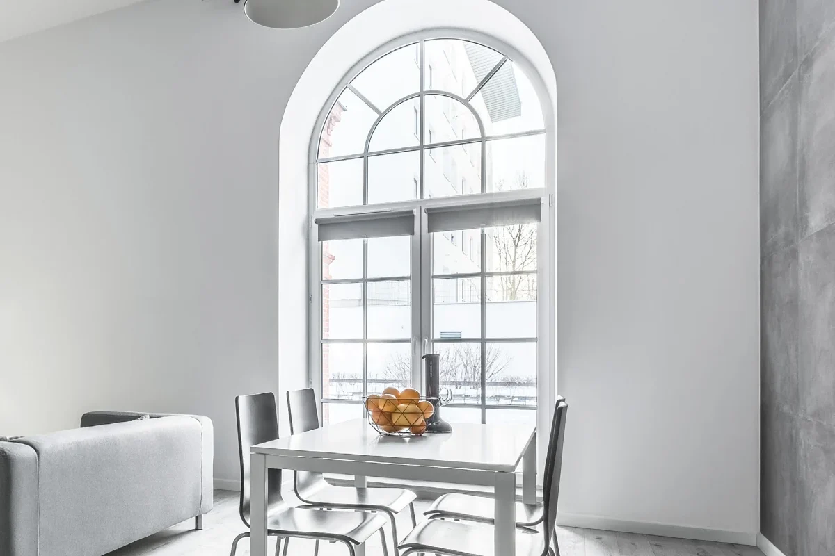 Salle à manger lumineuse avec grande fenêtre bois cintrée à petits bois