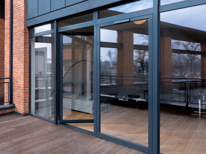 Terrasse en bois d'un immeuble avec portes vitrées aluminium anthracite