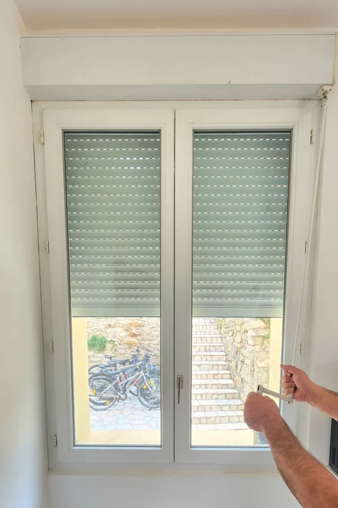 Volet roulant manuel sur fenêtre PVC blanche pendant un chantier de pose